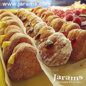 A delicious set of Mini Croissant Heart Donuts filled with Nutella, custard cream, and raspberry jelly, lightly coated with regular sugar and powdered sugar, arranged on a display tray. A perfect bite-sized indulgence for Valentine’s Day and special occasions.