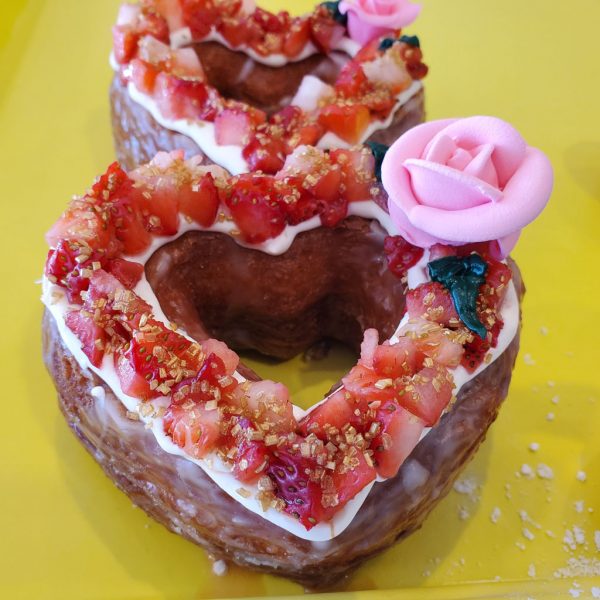 A beautifully crafted Valentine’s Strawberry Cream Cheese Croissant Heart Donut, topped with rich cream cheese frosting and decorated with fresh diced strawberries, placed on a golden, flaky croissant base. A luxurious and refreshing treat for Valentine’s Day.