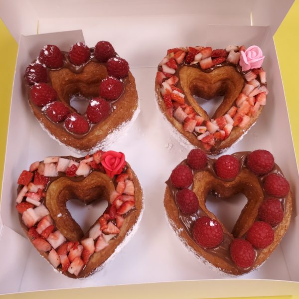 A beautifully crafted Valentine’s Strawberry Cream Cheese Croissant Heart Donut, topped with rich cream cheese frosting and decorated with fresh diced strawberries, placed on a golden, flaky croissant base. A luxurious and refreshing treat for Valentine’s Day.