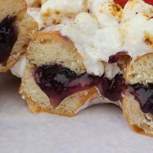 A Thanksgiving donut filled with purple yam jam, topped with marshmallows that are lightly torched for a roasted finish. The donut combines the creamy sweetness of purple yam with the toasty flavor of marshmallows.