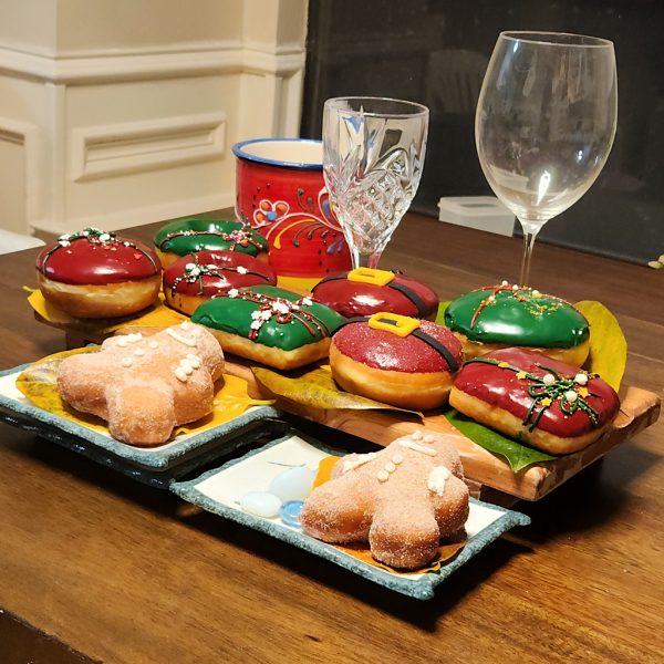 A gingerbread man-shaped donut, coated in sugar glaze, filled with spiced ginger cream cheese, and decorated with icing details, perfect for Christmas celebrations.