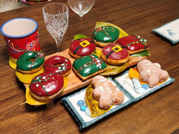 A gingerbread man-shaped donut, coated in sugar glaze, filled with spiced ginger cream cheese, and decorated with icing details, perfect for Christmas celebrations.