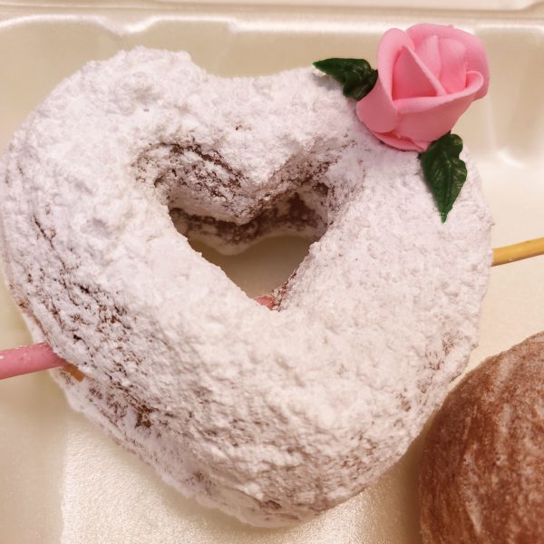 A beautifully crafted Valentine’s Powdered Sugar Croissant Cupid Donut, dusted with fine powdered sugar, topped with a delicate candy rose, and pierced with a strawberry cream Pocky stick as Cupid’s arrow. A crispy, flaky croissant donut perfect for Valentine’s Day.